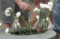 Asistentes al homenaje a las víctimas del atentado de Las Ramblas depositan flores en el memorial.