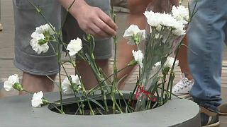 Asistentes al homenaje a las víctimas del atentado de Las Ramblas depositan flores en el memorial.