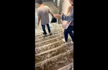 People walk as water rushes down the stairs following a heavy rainfall at Victor Hugo metro station in Paris, France August 16, 2022