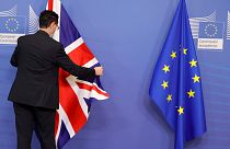 A member of protocol adjusts the EU and Union flag prior to an official greeting between the EU's Maros Sefcovic and the UK's Liz Truss,  in Brussels, Feb. 21, 2022.