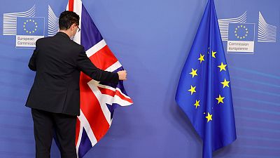 A member of protocol adjusts the EU and Union flag prior to an official greeting between the EU's Maros Sefcovic and the UK's Liz Truss,  in Brussels, Feb. 21, 2022. 