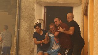 Una mujer es ayudada a salir de una casa por sus vecinos en Anón de Moncayo, España, el sábado 13 de agosto de 2022