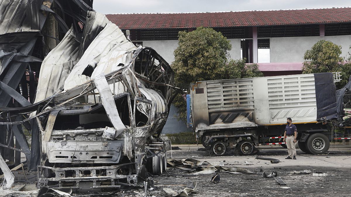 Un oficial tailandés junto a la cisterna de petróleo quemada en una gasolinera en la provincia de Pattani, en el sur de Tailandia, el miércoles 17 de agosto de 2022.