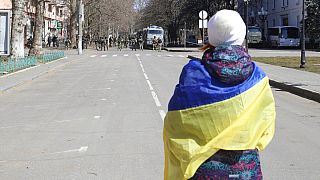 Egy nő ukrán zászlóval a vállán az oroszok kezére került Herszonban 2022 márciusában