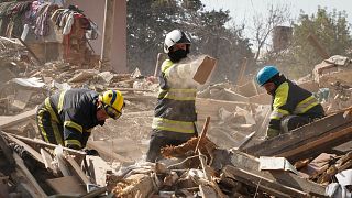 Des pompiers fouillent les décombres d'un bâtiment détruit lors d'un tir de missile à Kharkiv, en Ukraine, jeudi 18 août 2022.