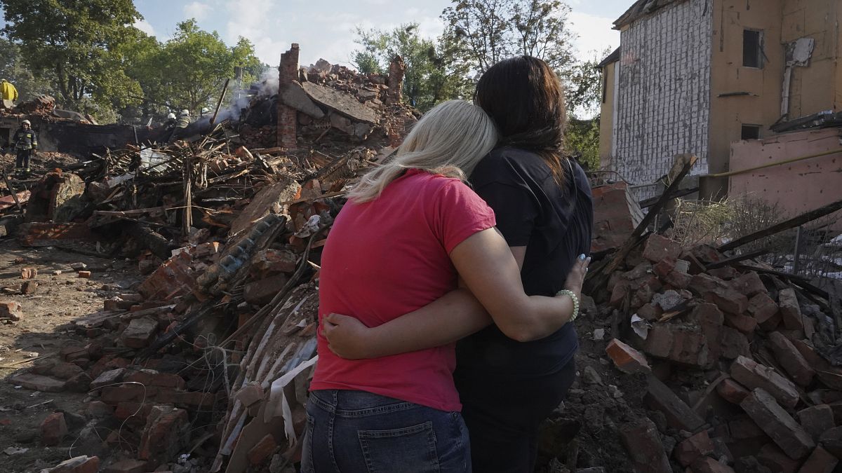 Украинки стоят перед разрушенным жилым домом в Харькове. 18 августа 2022.