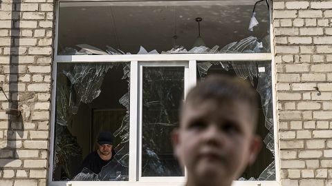A worker cleans up inside as Tikhon Pavlov, 11, walks past the Kramatorsk College of Technologies and Design after a rocket attack in the city. 