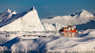قارب يحمل السياح بين الجبال الجليدية العائمة في خليج ديسكو، إيلوليسات، غرب غرينلاند، 1 يوليو 2022