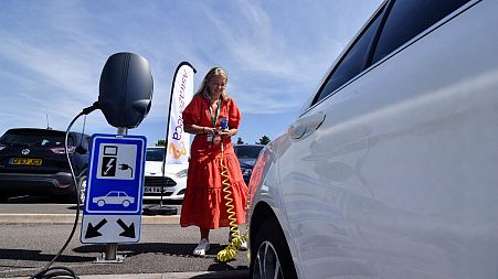 AstraZeneca's global head of sustainability plugs in a hybrid car at the company's manufacturing site in Macclesfield, UK, June 2022.