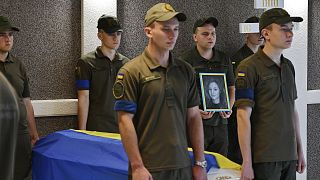 Ukrainian servicemen stand guard next to coffin of activist Julia Chaika during a funeral service in Zaporizhzhia, 21 August 2022