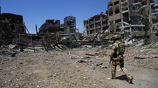 A Russian soldier walks in front of the damaged Metallurgical Combine Azovstal plant, in Mariupol, 13 June 2022