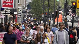 People walk along a shopping street in London