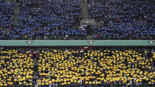Spectators hold banners in colors of the Ukrainian flag before a friendly charity soccer match between Legia Warszawa and Dynamo Kyiv in Warsaw, 12 April 2022