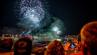 People look at fireworks over the Danube river and the parliament during celebrations to mark Hungary's national day in Budapest on August 20, 2021.