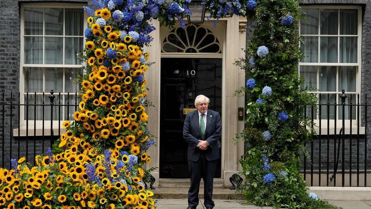 رئيس الوزراء البريطاني المنتهية ولايته بوريس جونسون أمام مقر رئاسة الوزراء في لندن وقد زينت بألوان العلم الأوكراني بمناسبة عيد العلم 