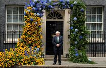 رئيس الوزراء البريطاني المنتهية ولايته بوريس جونسون أمام مقر رئاسة الوزراء في لندن وقد زينت بألوان العلم الأوكراني بمناسبة عيد العلم