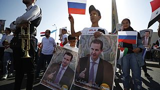 السوريون يحتفلون بيوم العلم الروسي في دمشق ويحملون ملصقات للرئيس السوري بشار الأسد، سوريا، الإثنين 22 آب / أغسطس 2022.