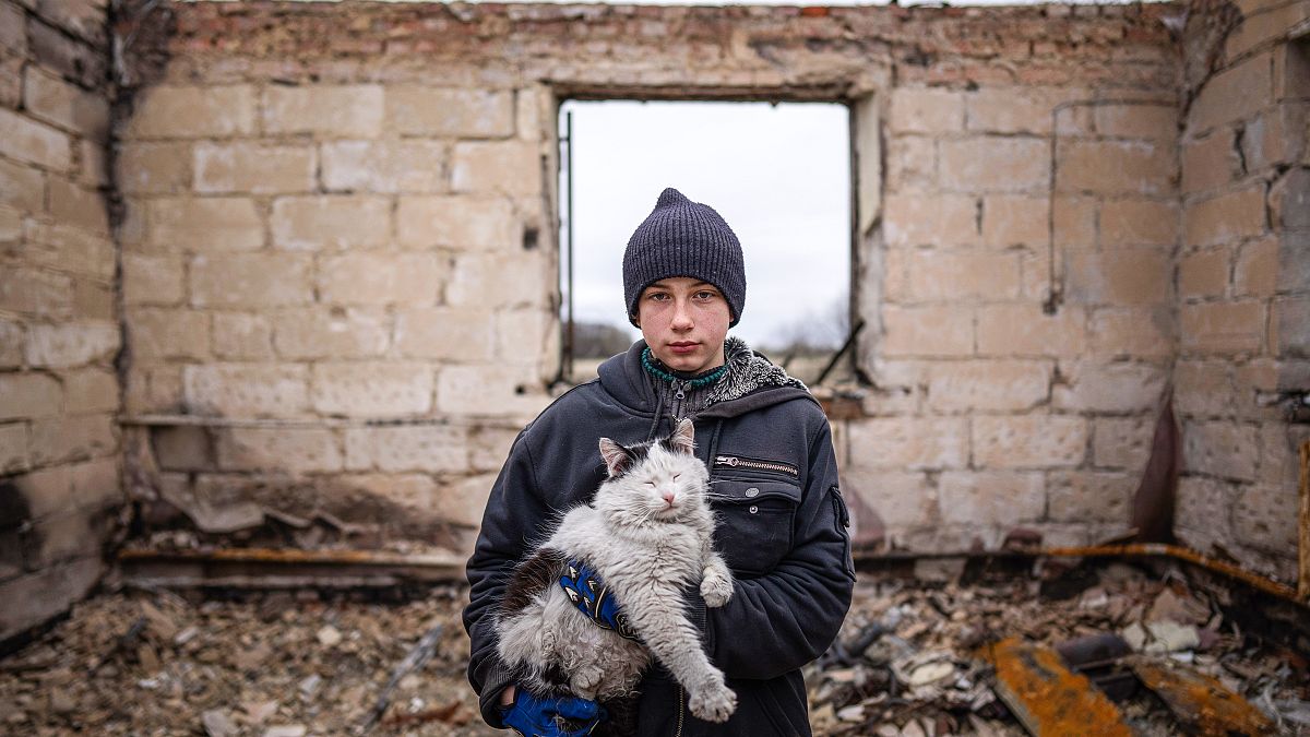 Danyk Rak, 12, holds a cat standing on the debris of his house destroyed by Russian forces' shelling in the village of Novoselivka, near Chernihiv, Ukraine. April 13, 2022. 