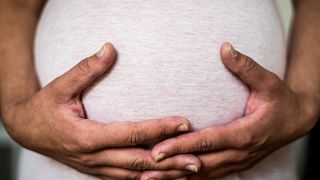 Egy várandós nő fogja a hasát