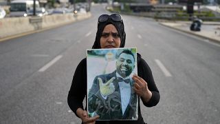 Rima Zahed tient le portrait de son frère décédé dans les explosions de 2020 pour demander aux autorités d'éteindre le feu qui détruit les silos à grains du port.
