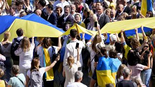 European Commission President Ursula von der Leyen marches alongside a giant Ukrainian flag during an event for Ukrainian Independence Day in Brussels, Wednesday Aug. 24 2022.