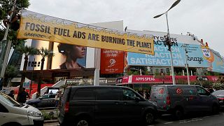 Greenpeace activists hold a banner that reads "Fossil fuel ads are burning the planet" during an action at the Festival Palace during the Cannes Lions International Festival.