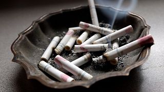 A cigarette burns in an ashtray.