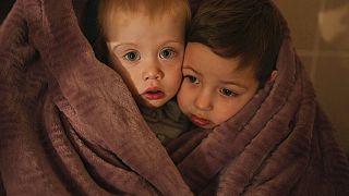 The children of medical workers warm themselves in a blanket as they wait for their relatives in a hospital in Mariupol, Ukraine, Friday, 4 March, 2022