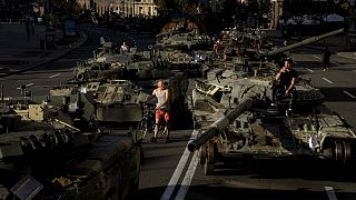 People walk around destroyed Russian military vehicles installed in downtown Kyiv, 24 August 2022