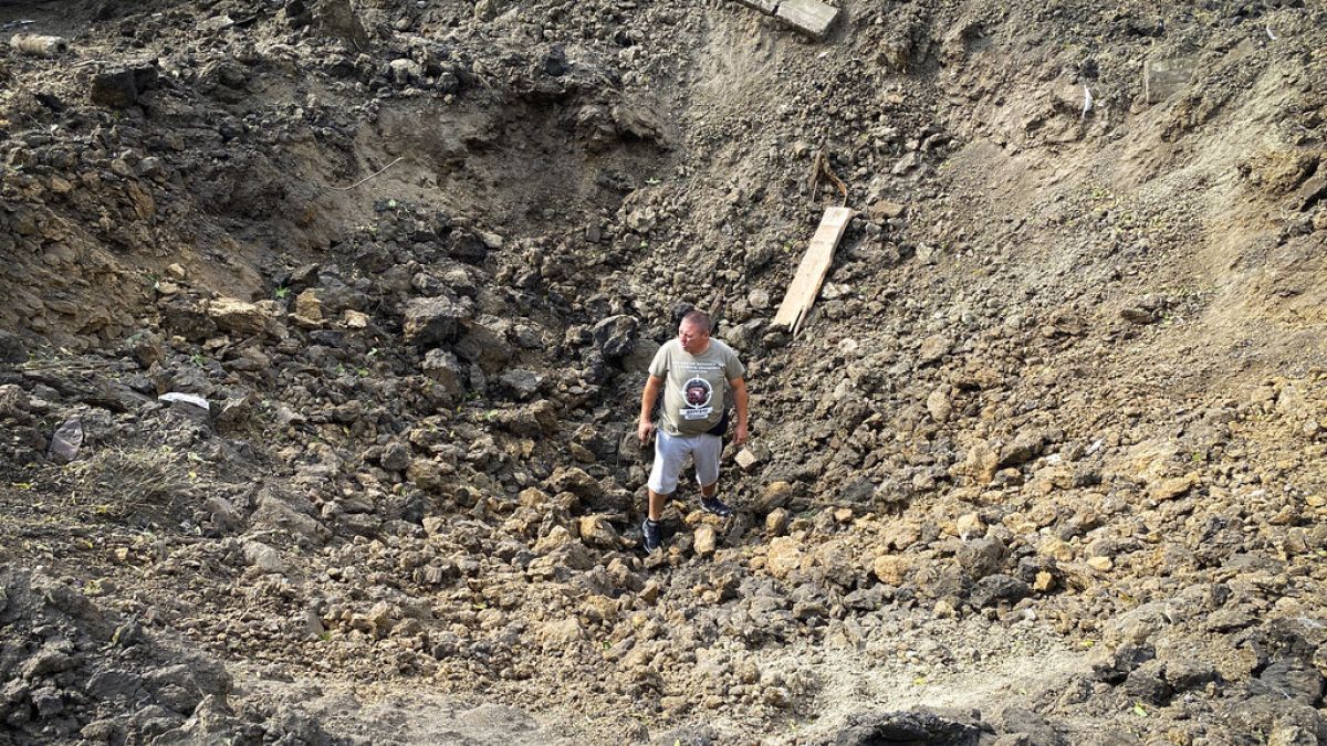 Местный житель стоит в кратере, оставшемся от удара российской ракеты. Дергачи, Донецкая область. 26 августа 2022.