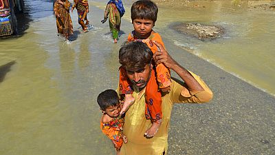 Un hombre lleva a sus dos hijos en brazos en una zona inundada de Jaffarabad, en la provincia de Baluchistán 