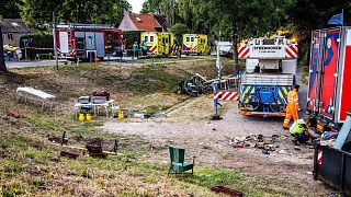 Emergency services operate at the scene of an accident after a lorry drove off a dike into a neighborhood party, 27 August 2022