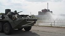 A Russian tank cruises past the nuclear plant