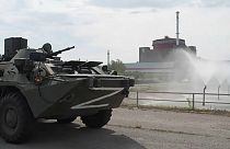 A Russian tank cruises past the nuclear plant