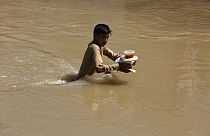 Aşırı yağışların neden olduğu sel nedeniyle evinden kaçan ve kendilerine verilen yemeği taşımaya çalışan bir çocuk.  Peşaver / Pakistan