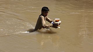 Aşırı yağışların neden olduğu sel nedeniyle evinden kaçan ve kendilerine verilen yemeği taşımaya çalışan bir çocuk.  Peşaver / Pakistan