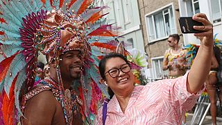 Un danseur pose pour un selfie avec une spectatrice venue admirer la parade principale du carnaval de Notting Hill