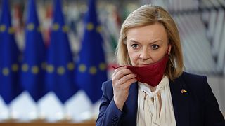 Liz Truss, then UK foreign secretary, takes off her protective face mask as she arrives for an EU foreign ministers meeting in Brussels