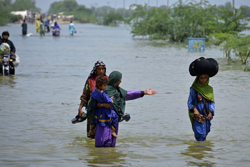 People wade through floodwaters in Sohbatpur, a district of Pakistan's southwestern Baluchistan province, 29 August 2022.
