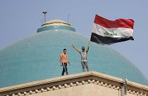 Supporters of Shiite cleric Muqtada al-Sadr wave a national flag from the roof of the Government Palace during a demonstration in Baghdad, 29 August 2022