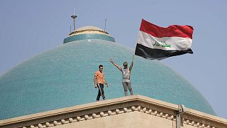 Supporters of Shiite cleric Muqtada al-Sadr wave a national flag from the roof of the Government Palace during a demonstration in Baghdad, 29 August 2022
