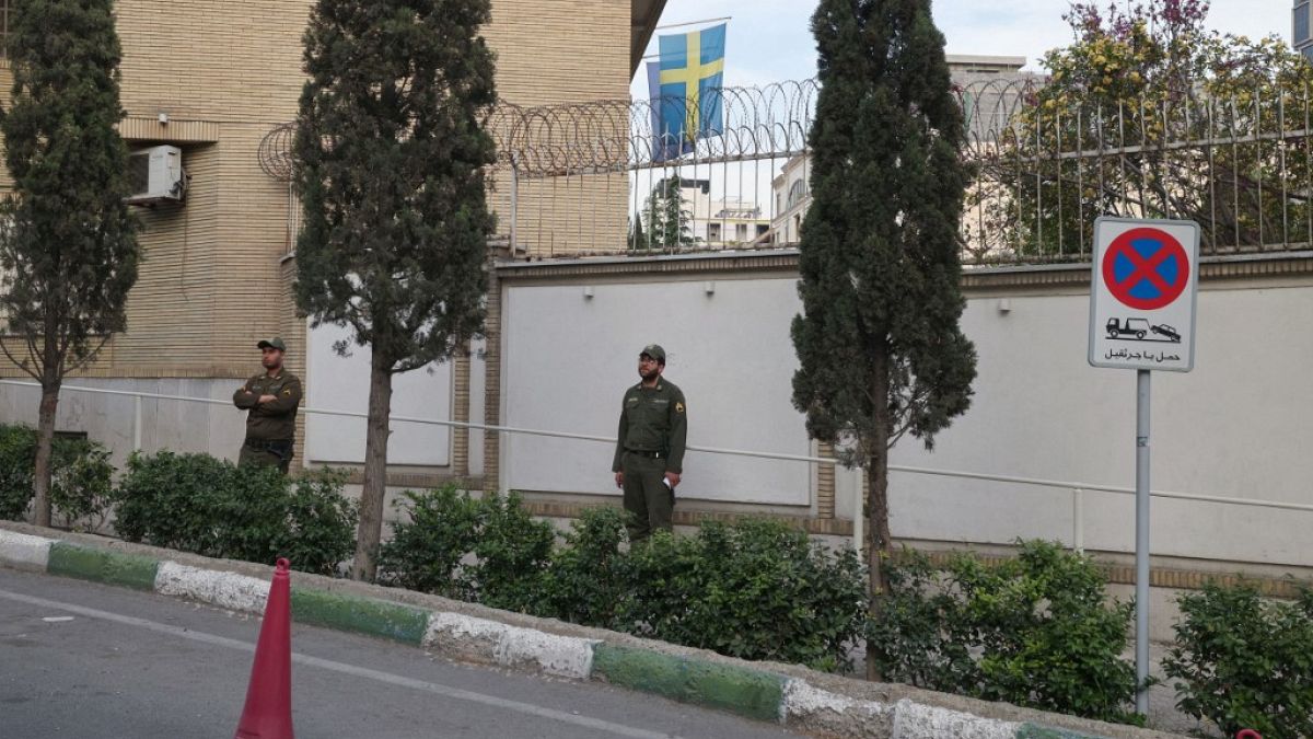 Members of Iranian security forces stand guard in front of the embassy of Sweden in Tehran.