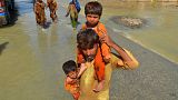 A displaced man carries his daughters through a flooded area in Jaffarabad, Pakistan, 27 August.