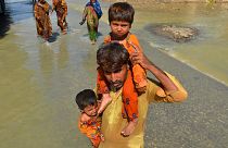 A displaced man carries his daughters through a flooded area in Jaffarabad, Pakistan, 27 August.