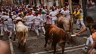 Emberek rohannak Pamplona utcáin a hagyományos bikaviadal előtt 2022. július 14-én