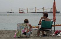 Dos mujeres observan el buque varado frente a la costa, en la Bahía de Gibraltar, tras sufrir una colisión
