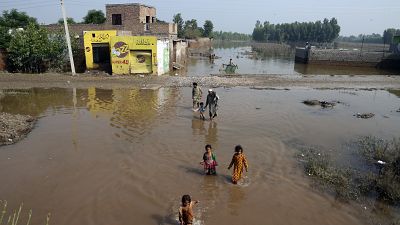 Des personnes pataugent dans les eaux de crue à Charsadda au Pakistan