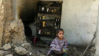 Ein Mädchen sitzt in den Trümmern ihres Zuhauses in Charsadda, Pakistan