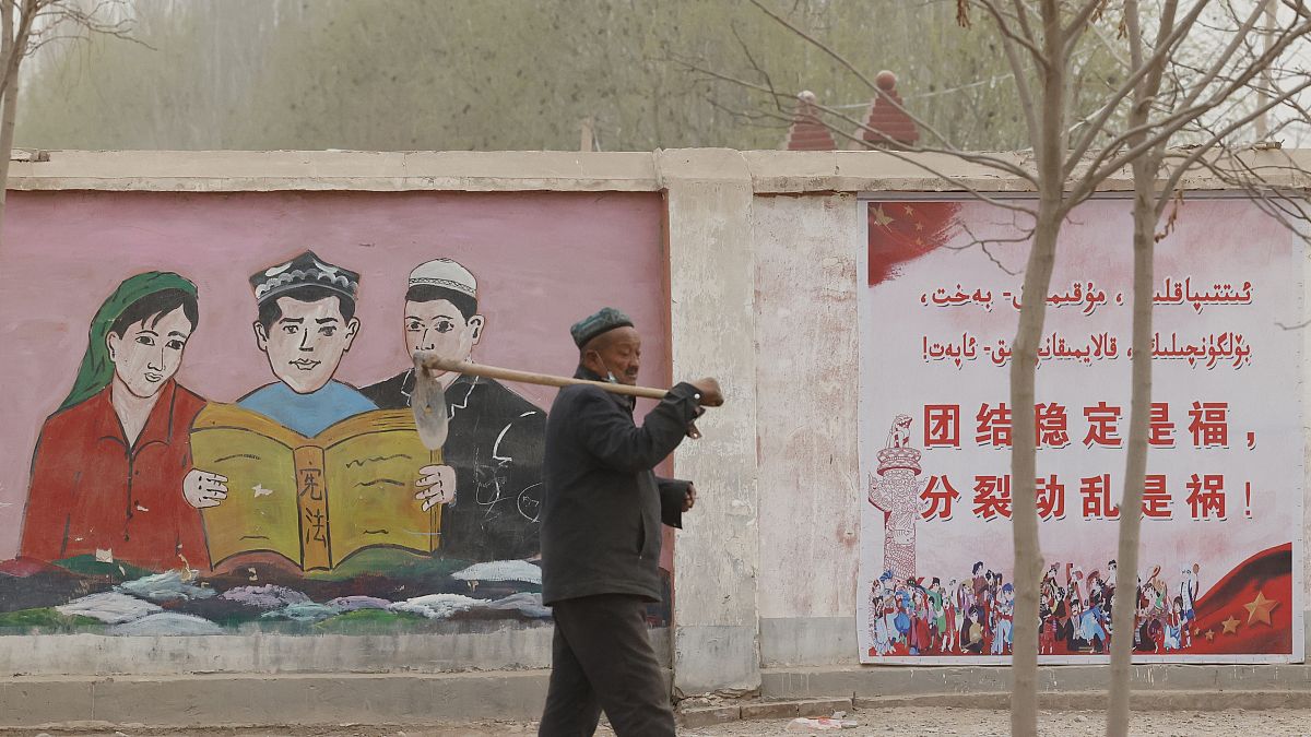 Egy férfi sétál az etnikai kisebbségek ábrázoló kormányzati propagandaplakát előtt 