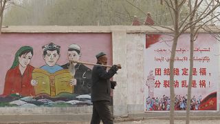 Egy férfi sétál az etnikai kisebbségek ábrázoló kormányzati propagandaplakát előtt